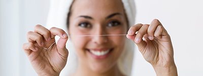 Woman smiling while holding up floss