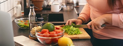 Closeup of woman cutting vegetables on cutting board