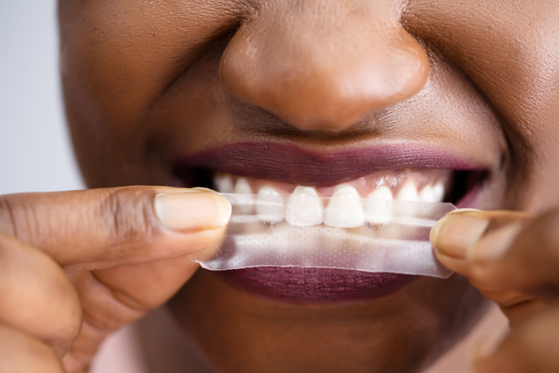 Patient putting on a teeth whitening strip